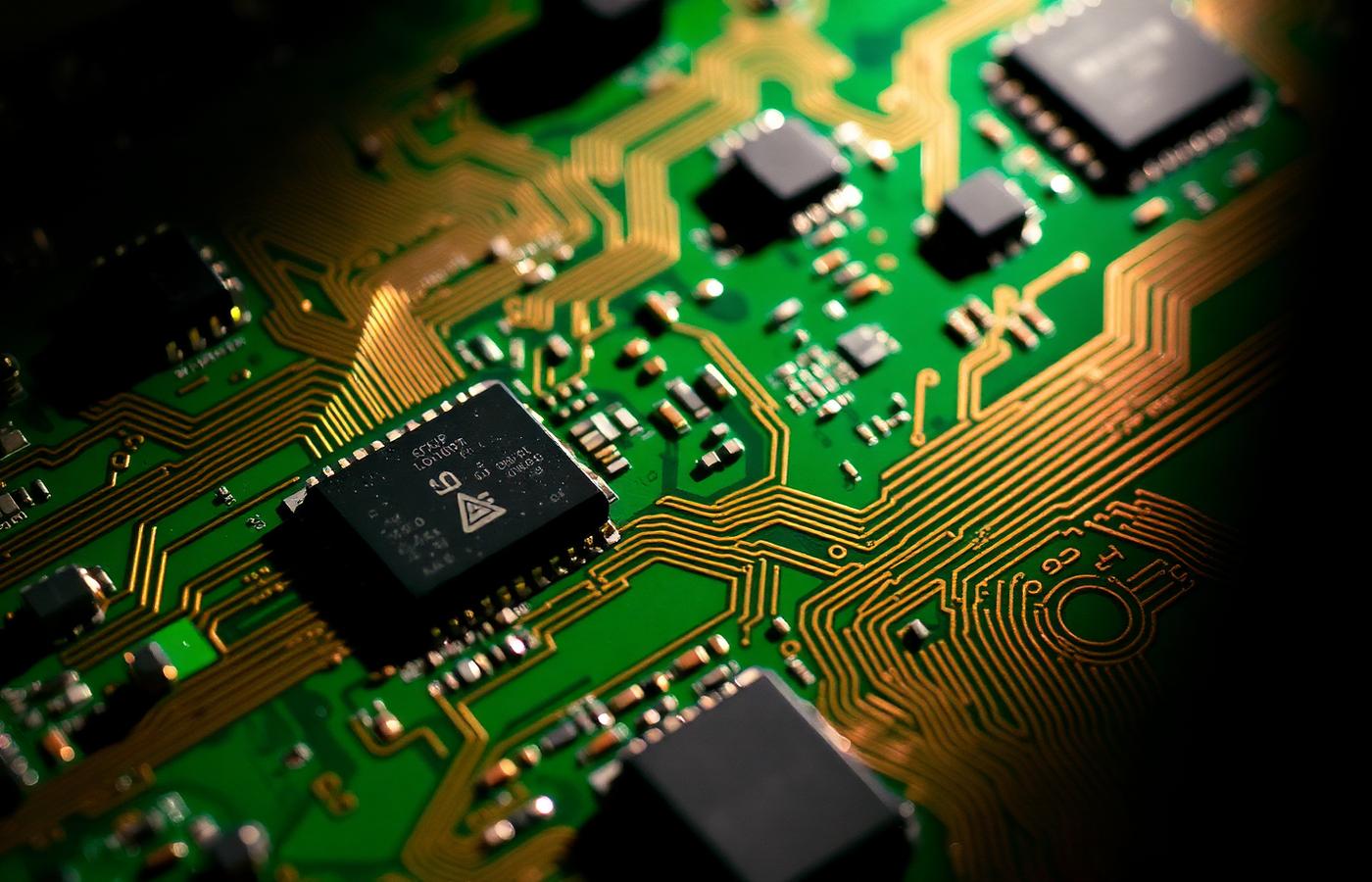 Macro photograph of a circuit board showing copper traces and microchips
